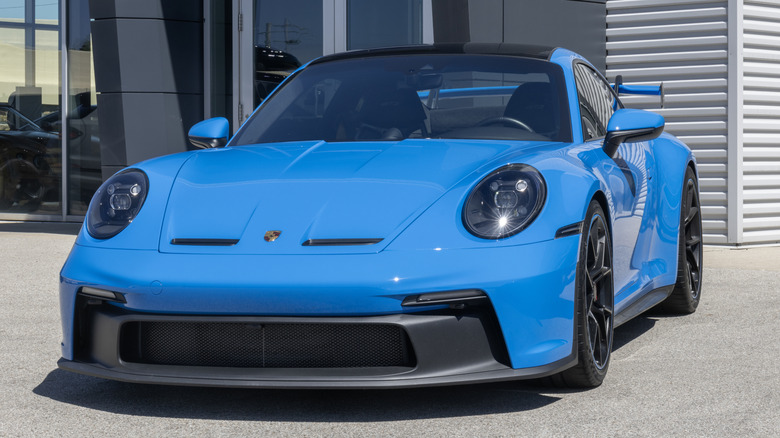 A blue Porsche 911 GT3 parked in front of a dealership.