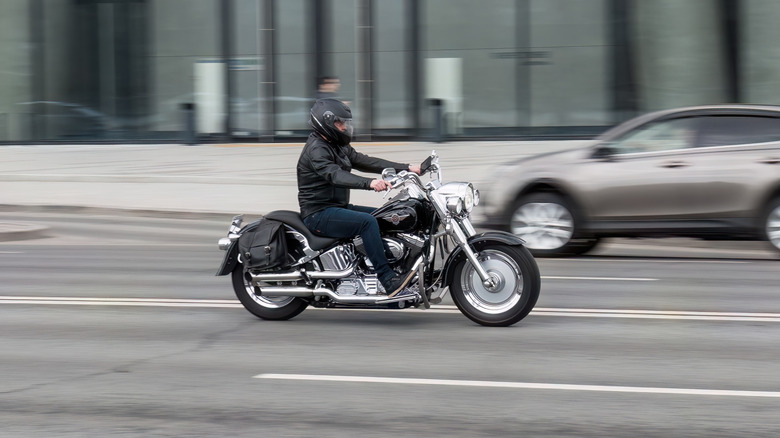A rider riding Harley-Davidson Fat Boy along the highway, side view