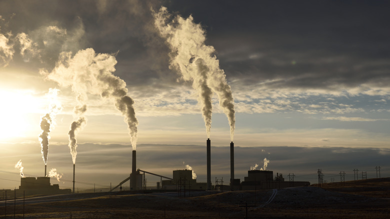 Coal-fired power plant in operation with smoke coming out of stacks and dark clouds overhead