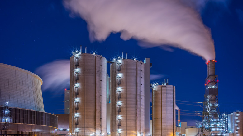 Coal-fired power plant, lit up at night with smoke coming out of stack