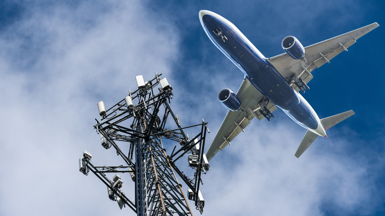 Cell tower with airplane flying over it