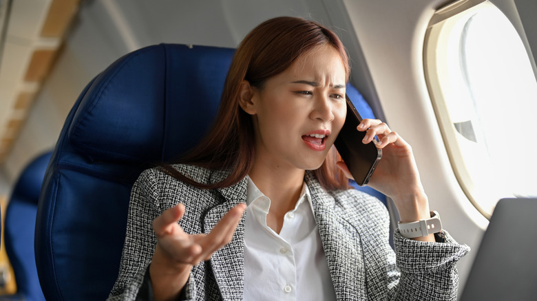 angry businesswoman on call in plane