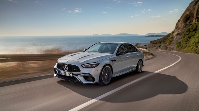 The Mercedes C 63 E Performance on the move in silver, front 3/4 view, coastal road