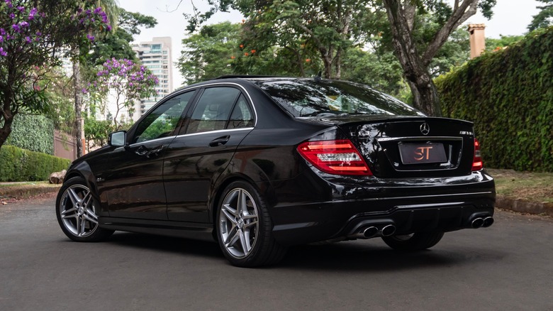 Rear three-quarter view of a black Mercedes-Benz C63 AMG on a suburban street