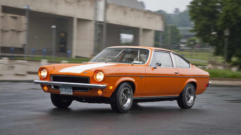 Orange 1973 Chevrolet Vega driving in empty parking lot