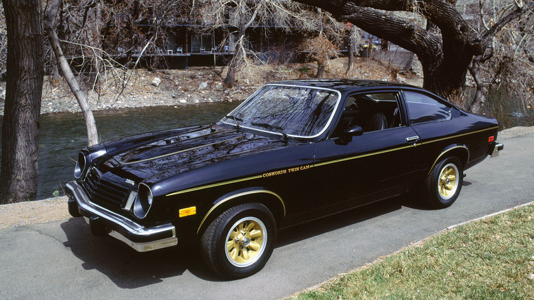 Black 1975 Chevrolet Vega parked on country road with trees and river in background