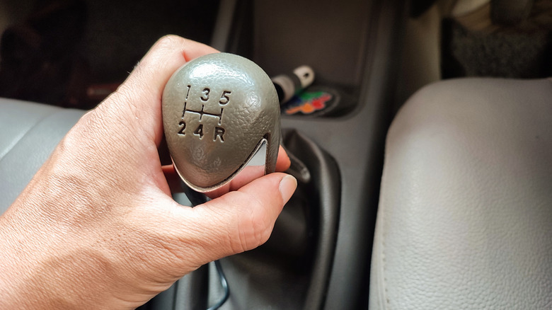 Close-up of person's hand resting on 5-speed manual transmission shifter