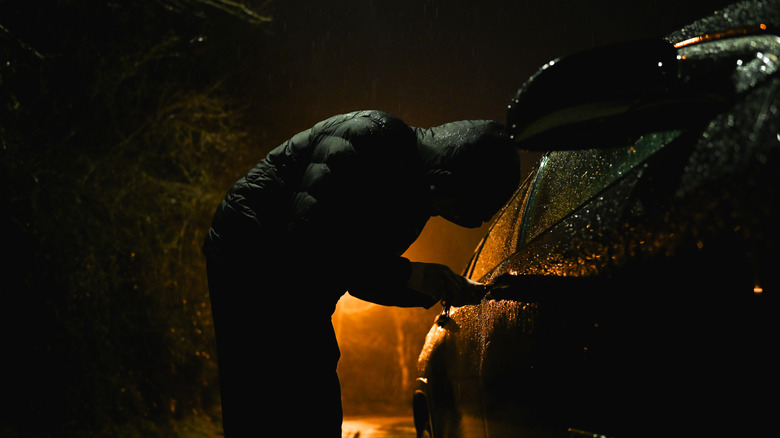 Carjacker breaking into sedan right-hand side door at night