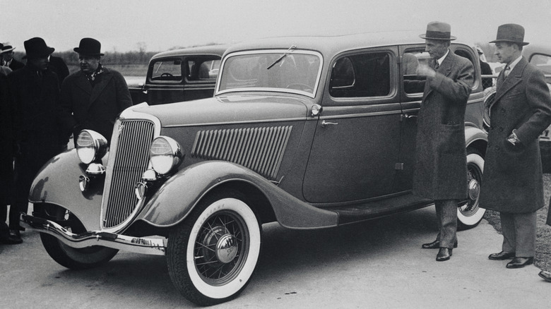 Men standing next to 1934 Ford Model V