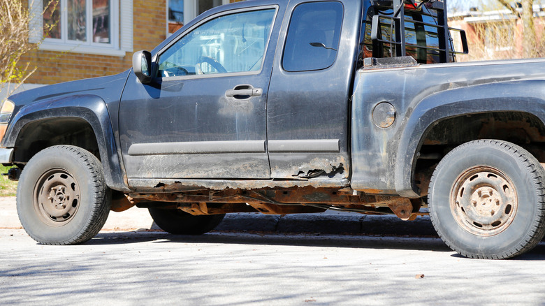 A profile shot of a pickup truck showing extensive rusting underneath the cab