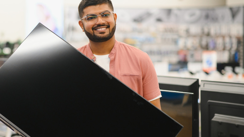 Man holding new TV in electronics store