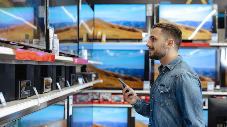 Man browsing TVs in electronics store