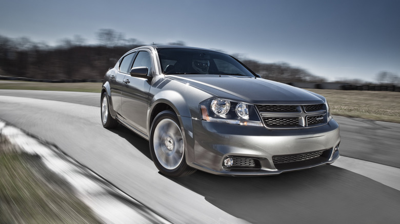 A gray 2012 Dodge Avenger at speed, front 3/4 view