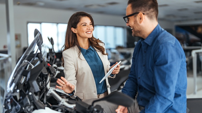 cheerful saleswoman engages with a customer discussing motorcycle options