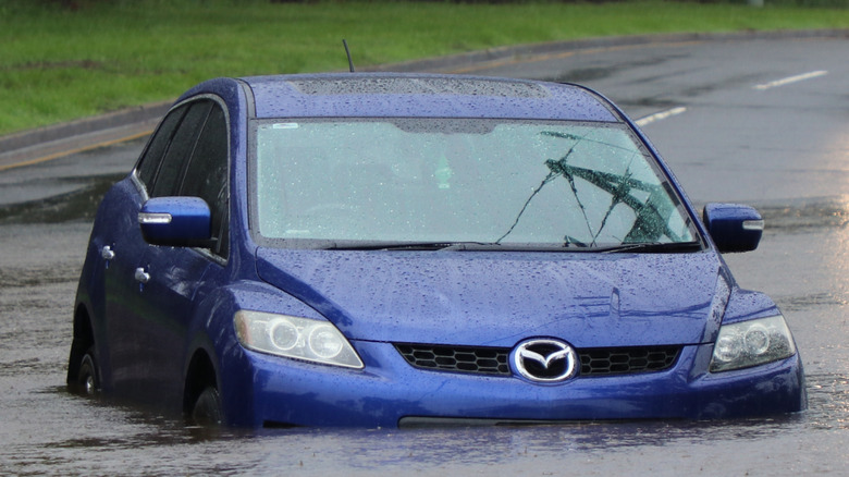 A blue car in floodwaters up to the bottom of its doors