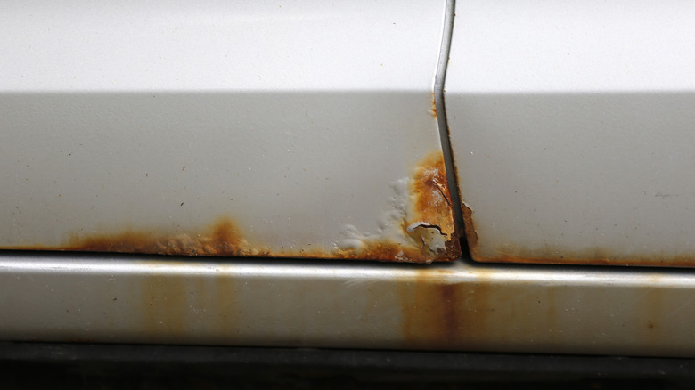 Bubbled paint and rust on the bottom edge of a silver car door