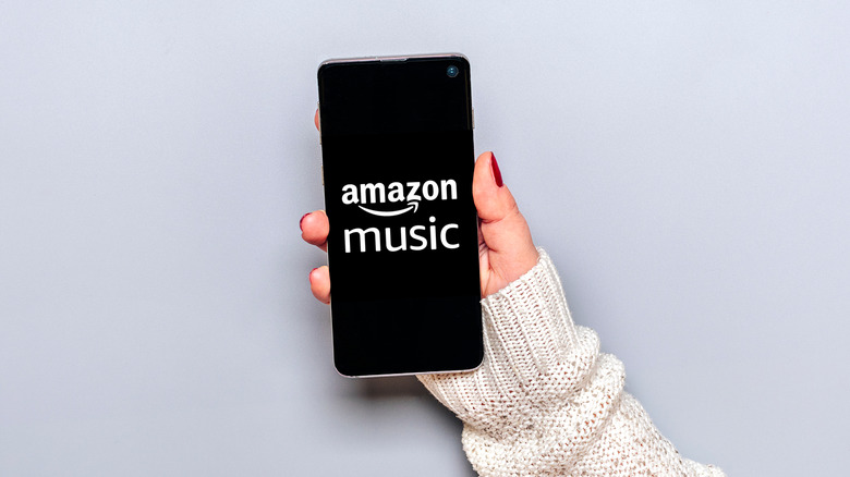 Woman holding smartphone with Amazon music on the screen