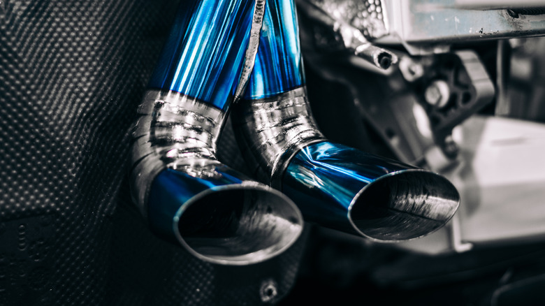 A custom titanium exhaust system on a mid-engined car, showing the blue pipe and the intricate welds