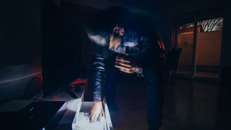 Blurred security camera footage of a burglar inside a house