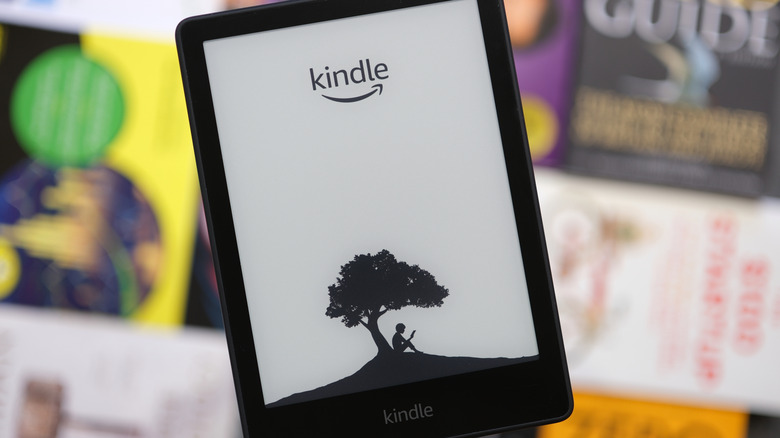 Close-up of a Kindle with blurred books in the background