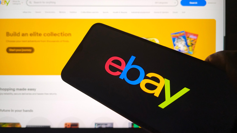 Smartphone displaying the ebay logo in front of a laptop screen