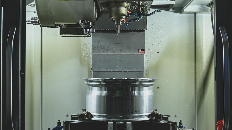 an aluminum wheel being forged and milled.