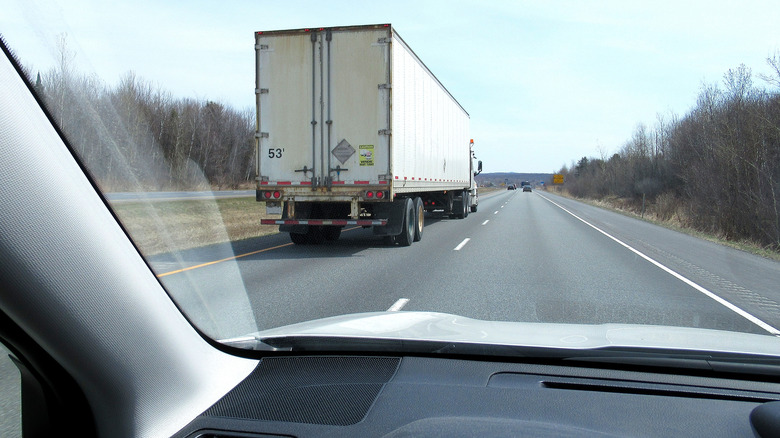 Inside a passenger car looking at a semi truck on the left