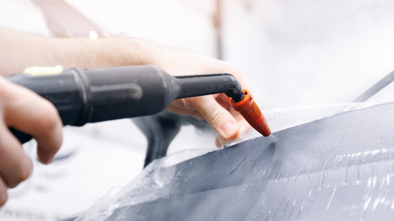 Man spraying vinyl car wrap with tool