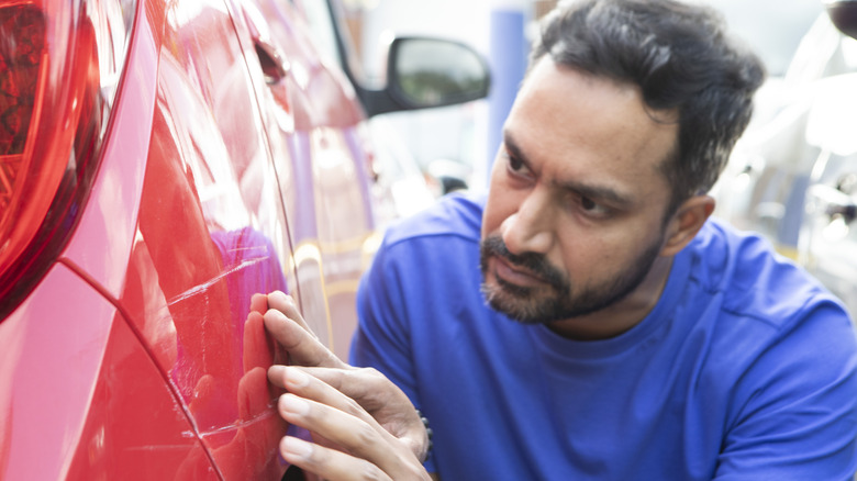 A man examining damage to a car's bodywork