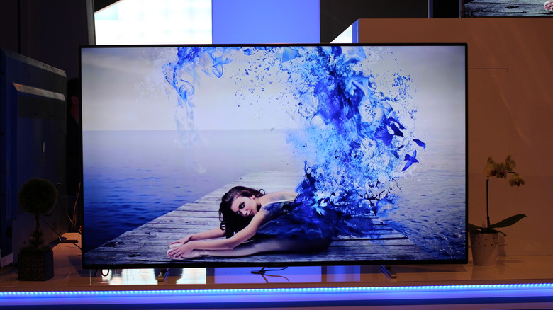 An OLED TV on a stand with blue lighting