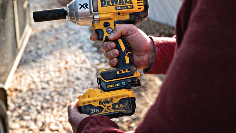 A person places a battery pack on a DeWalt power drill
