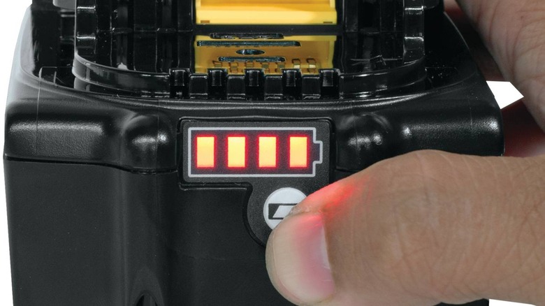 A person lights up the power indicator on a Makita battery