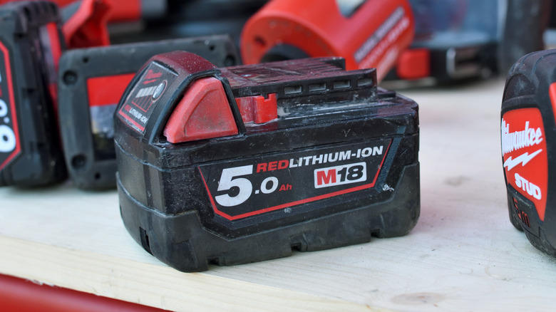 Milwaukee power tool batteries on a wood surface