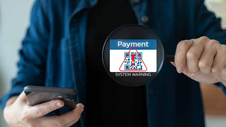 Smartphone QR code payment system showing a warning alert for fraud