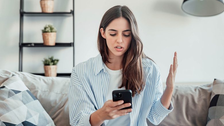 A young woman frustrated expression with mobile in her hands
