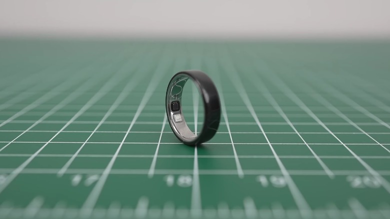 An Oura 5 ring on a gridded green surface.