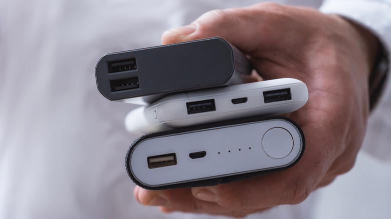 Person holding a stack of three power banks in one hand
