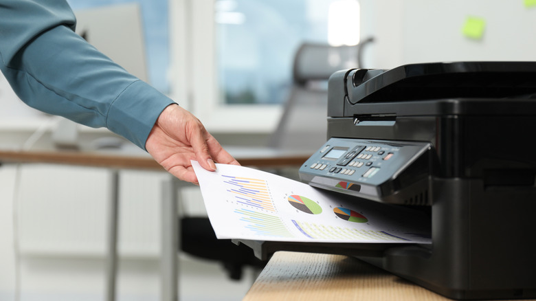 A woman taking a paper from a printer