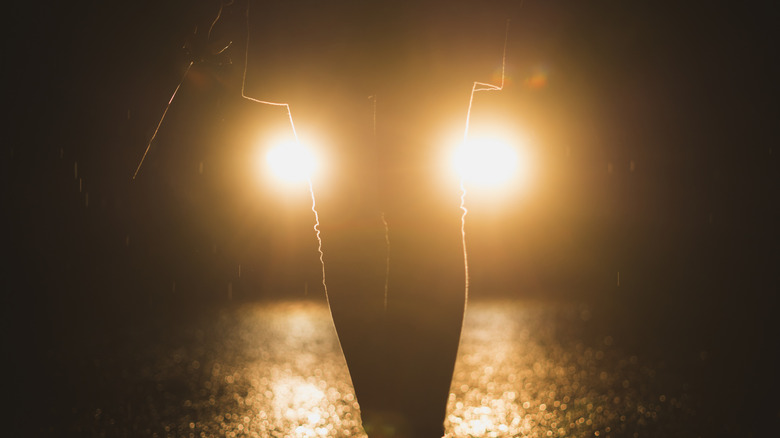 Person standing in front of a car with halogen headlights