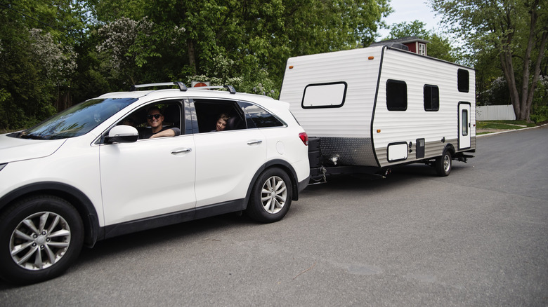 A white Kia Sorento SUV towing a camper