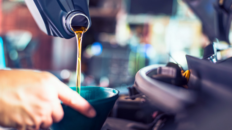 Mechanic pouring oil in car