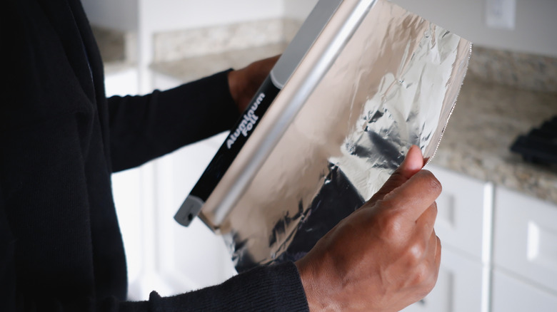 Pulling a sheet of aluminum foil from the roll