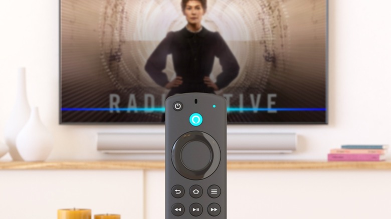 Amazon Fire TV remote in front of TV showing a show