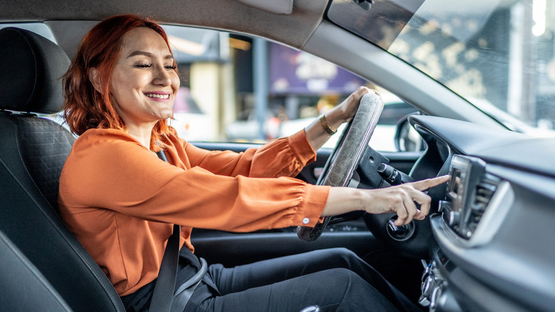 A driver pressing a button on a car stereo.