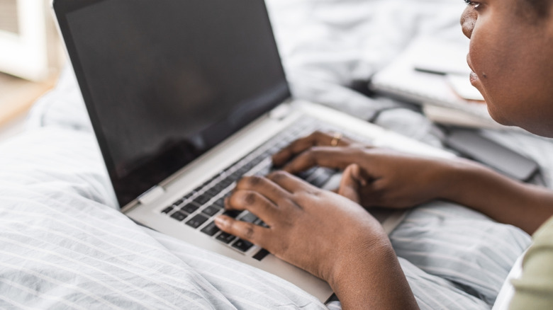 Las mujeres usan la computadora portátil en la cama