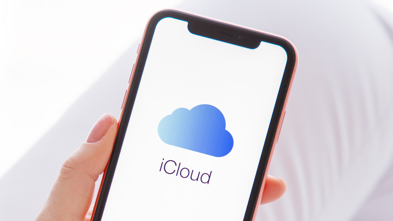 woman holding smartphone with iCloud logo on the screen