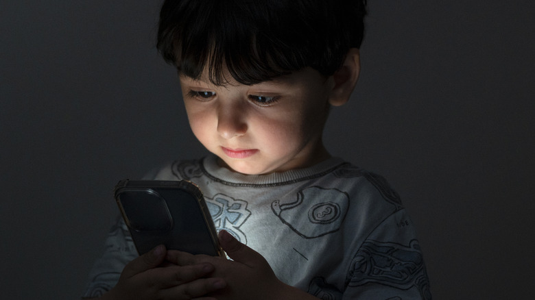 child in the dark, illuminated by smartphone screen
