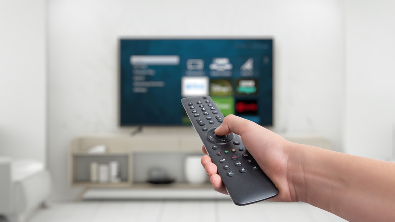 A hand holding a remote control for a smart TV