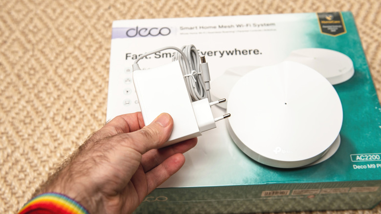 A man holding the Deco AC220 M9 Plus Tp-Link mesh system
