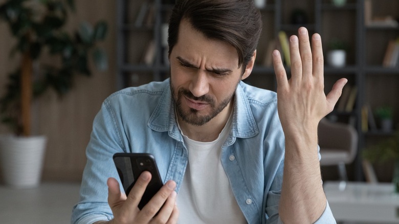 frustrated man looking at phone 